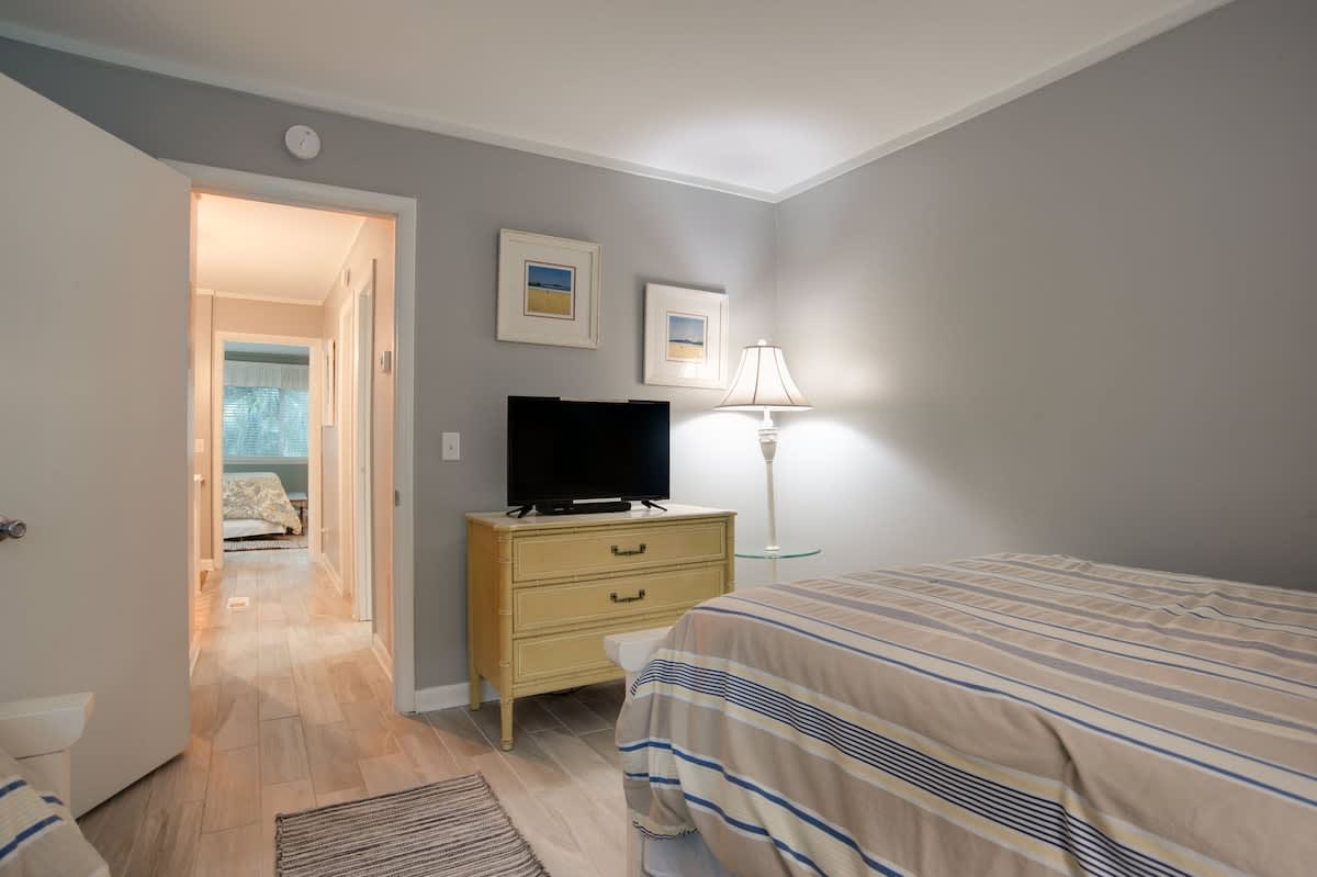 Your peaceful bedroom features soothing gray walls, warm wood floors, and a cozy lamp creating the perfect atmosphere for restful nights.