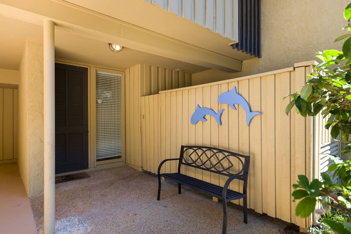 Your private covered patio welcomes you with playful dolphin art and a cozy bench for morning coffee or evening relaxation.