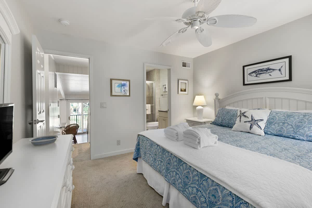 Drift off in your serene coastal retreat, where soft blue linens and gentle ceiling fan breezes create perfect comfort for peaceful nights.