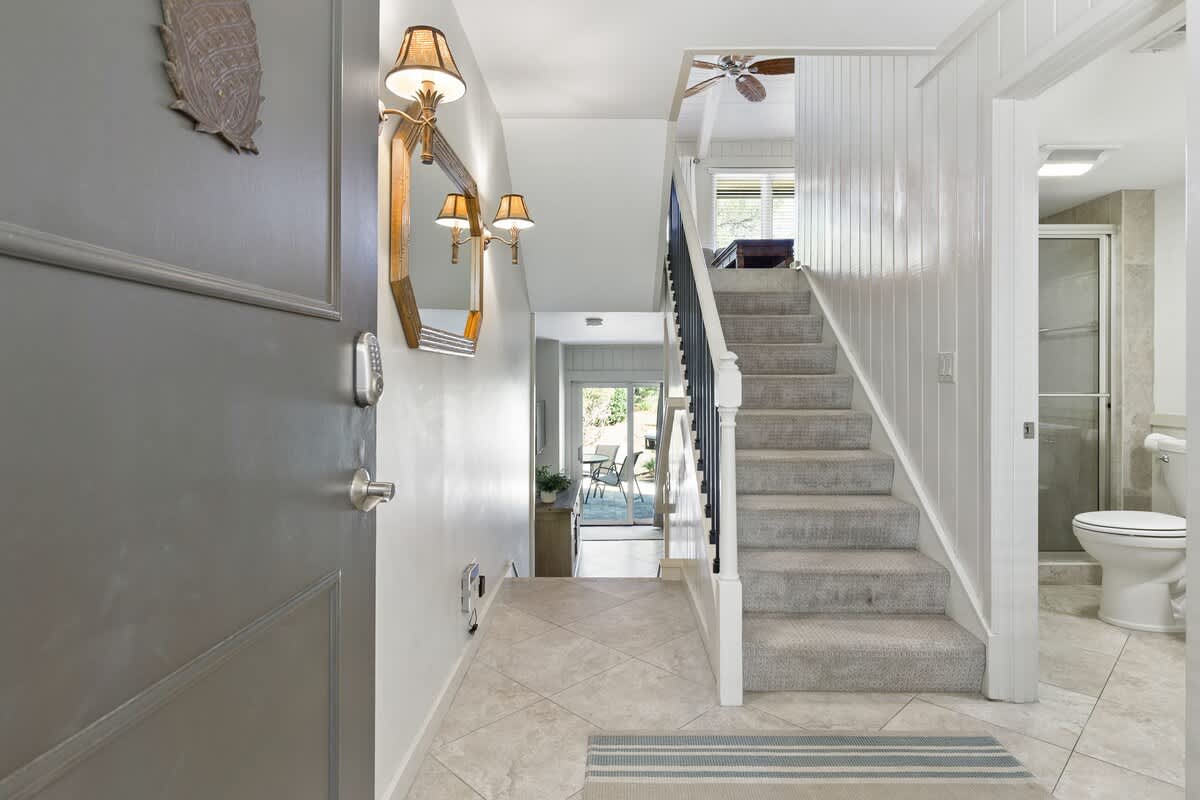 Your bright entryway welcomes you with coastal charm - carpeted stairs lead to peaceful retreats while elegant lighting sets a relaxing mood.