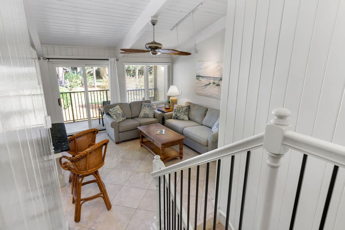 Relax in your bright living area with vaulted ceilings, cozy sectional seating, and peaceful balcony views through French doors.