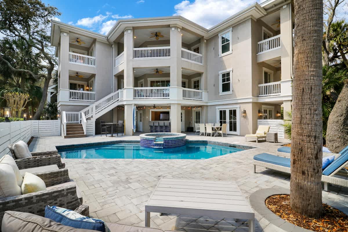 Stunning three-story beachside villa with private pool and spacious outdoor entertaining area surrounded by tropical palms.