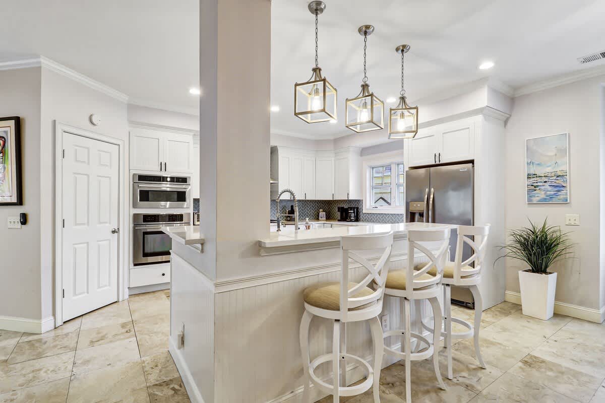 Your modern kitchen invites culinary adventures with sleek white cabinets, granite counters, and stylish pendant lighting creating the perfect gathering spot.