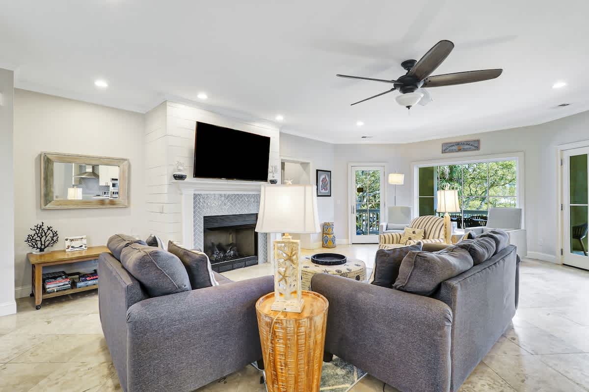 Relax in your stylish living space with a cozy fireplace, entertainment center, and ceiling fan creating the perfect atmosphere for memorable evenings.