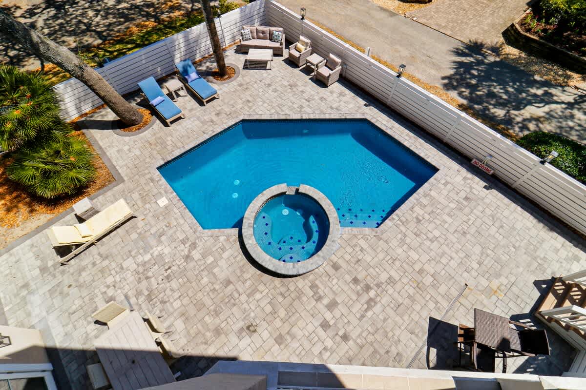 Aerial view of the property's pool area with patio seating and tropical landscaping surrounding the accommodation.