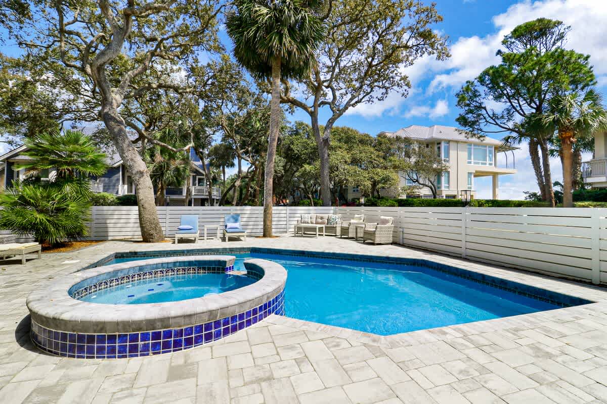 Dive into your private oasis featuring a sparkling pool and relaxing hot tub, surrounded by lush tropical palms.