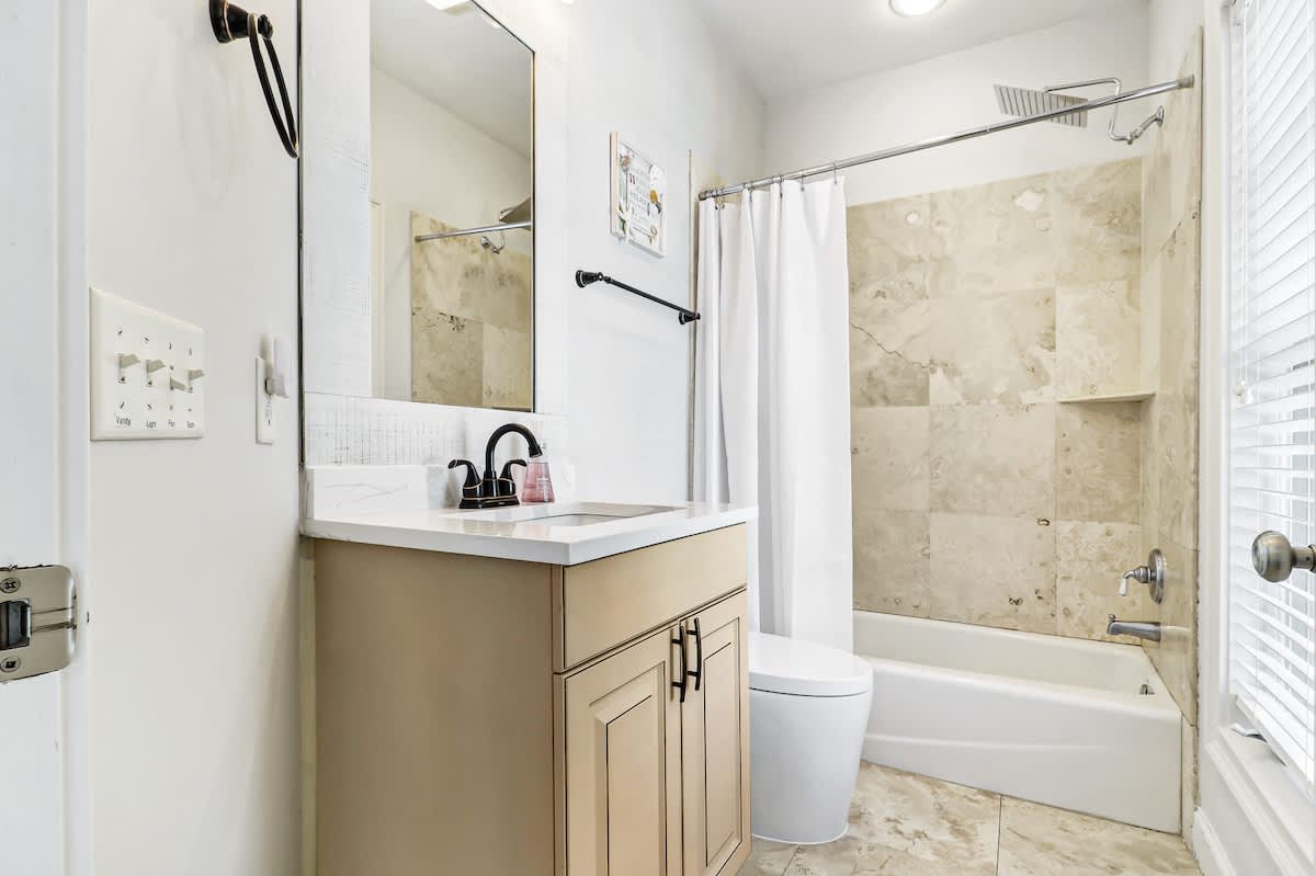 Step into your sparkling clean bathroom featuring marble-style tiling, a spacious tub-shower combo, and modern vanity with ample counter space.