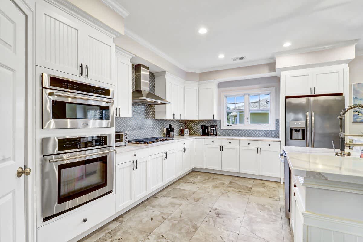 Your gourmet kitchen features crisp white cabinetry, sleek stainless steel appliances, and elegant marble countertops for memorable meal preparation.