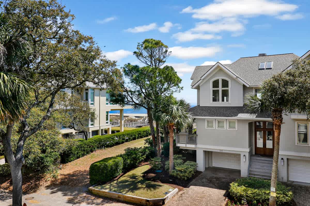 Elegant coastal home nestled among lush palms and mature trees, creating a peaceful retreat setting.