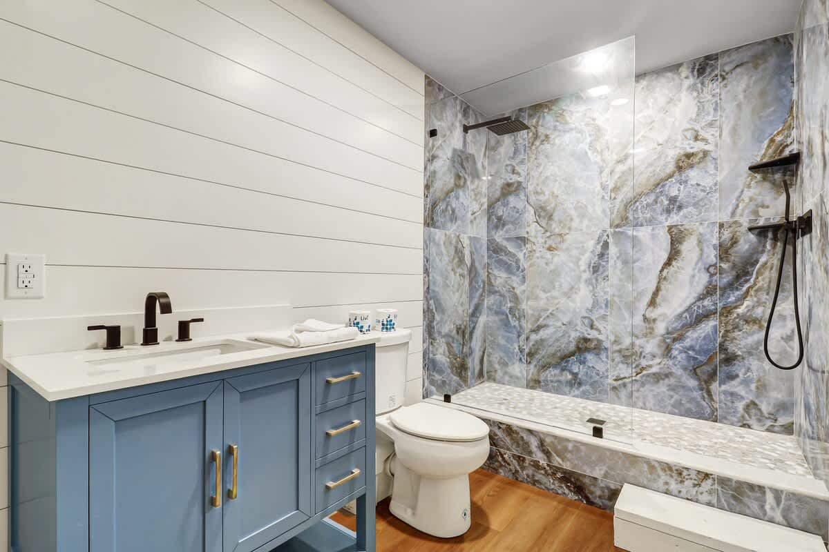 Stylish ground-level full bathroom featuring a walk-in shower, modern vanity, and direct access from the pool area for added comfort and convenience.