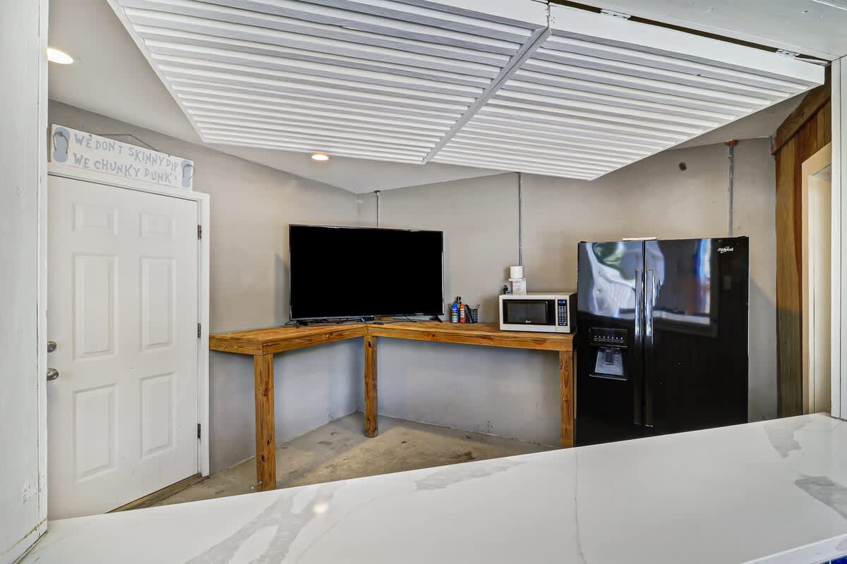 Your cozy retreat features a well-equipped kitchenette with modern appliances, entertainment center, and comfortable sleeping space under stylish exposed beams.