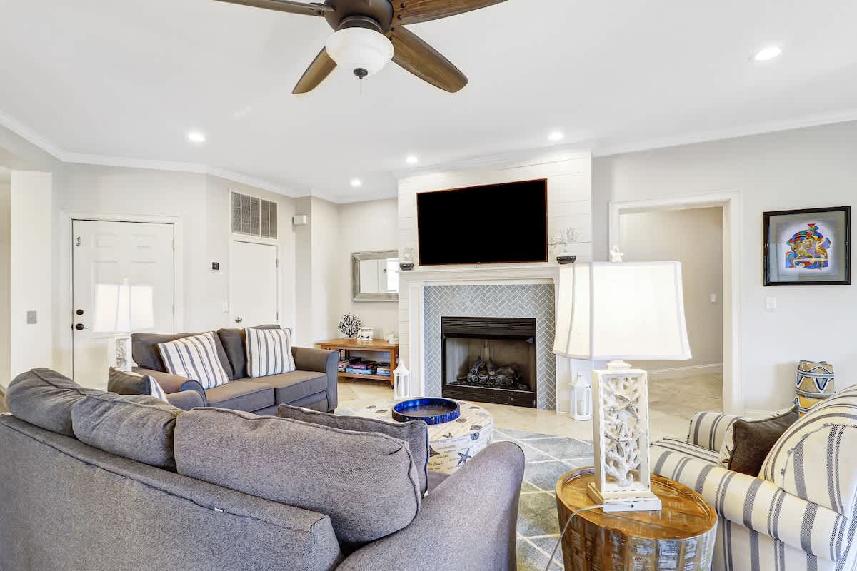 Unwind in your elegant living room with cozy seating, flickering fireplace, and ceiling fan keeping you perfectly comfortable.