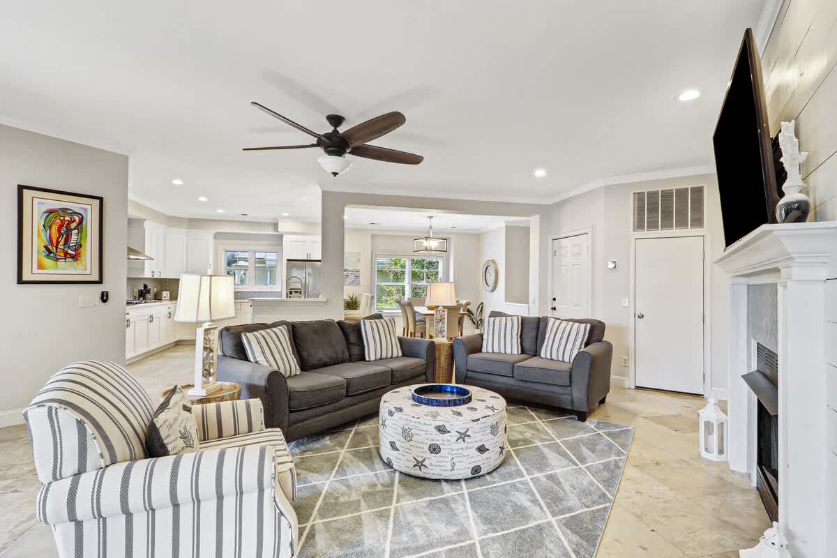 Relax in your open-concept living space with stylish gray sofas, coastal decor, and a cozy fireplace for perfect evenings in.