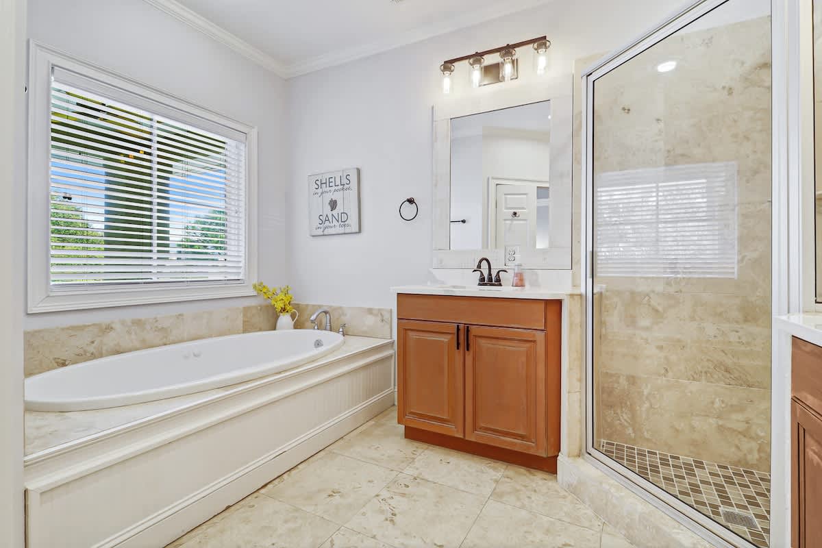 Unwind in your luxurious bathroom featuring a deep soaking tub, spacious walk-in shower, and coastal charm.