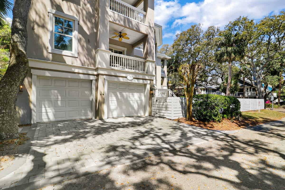 Modern three-story property with dual garage spaces and tropical landscaping in a quiet residential neighborhood.