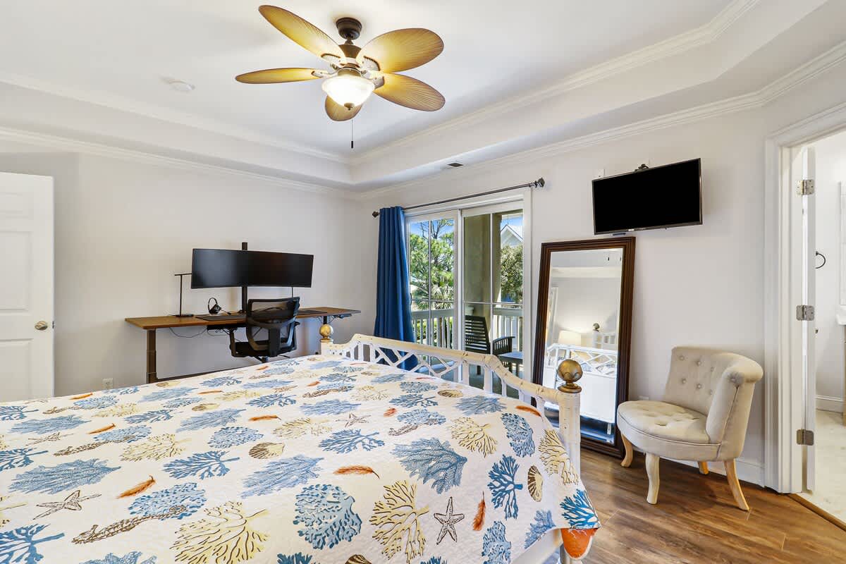 Relax in your coastal-inspired bedroom with tropical ceiling fan, work desk, and balcony access for fresh air.