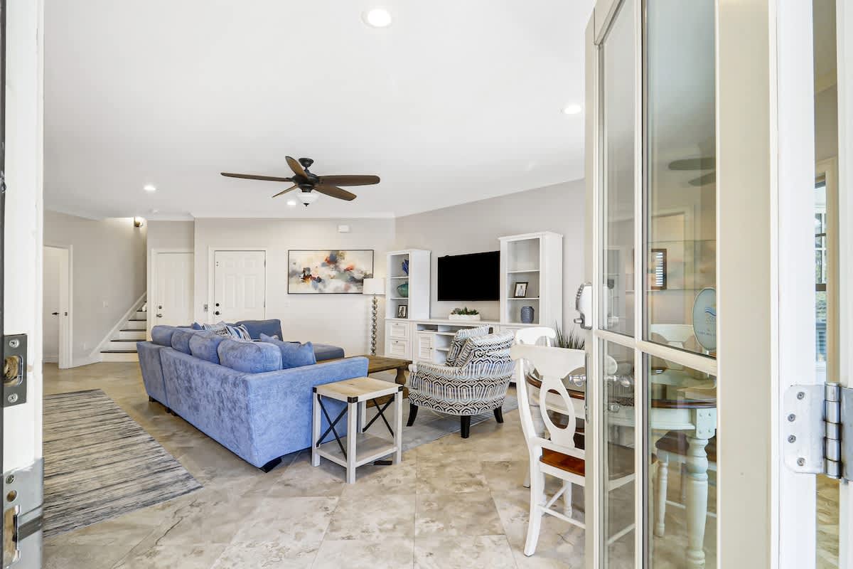 Relax in your spacious living room with plush blue seating, modern entertainment center, and natural stone floors.