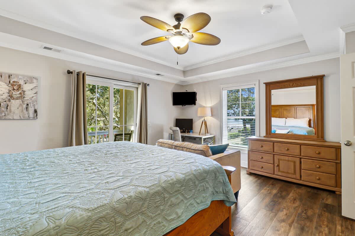 Unwind in your spacious bedroom with elegant tray ceiling, tropical breeze from the ceiling fan, and views of lush greenery.