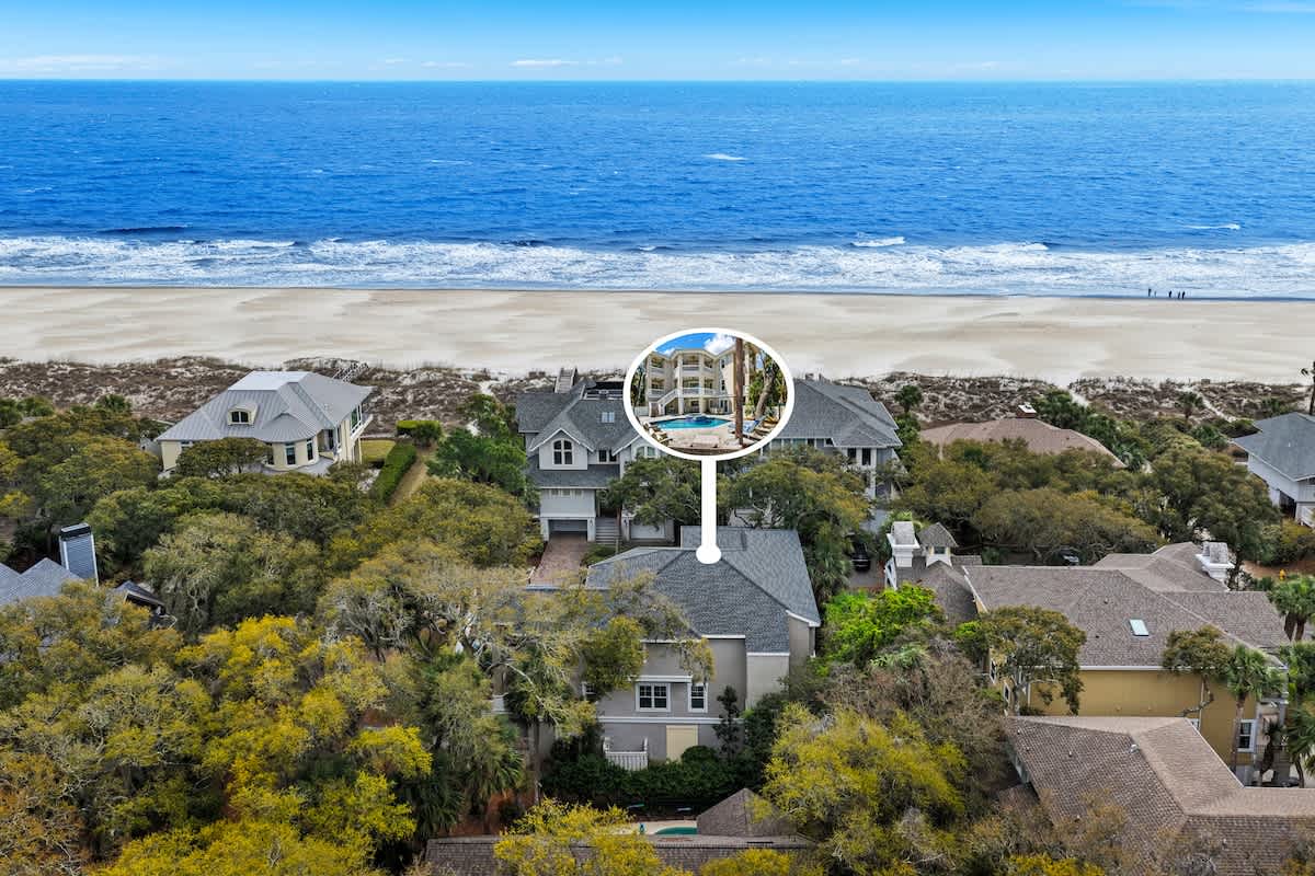 Aerial view of beachfront properties nestled among lush vegetation, just steps from pristine sandy shores and rolling ocean waves.