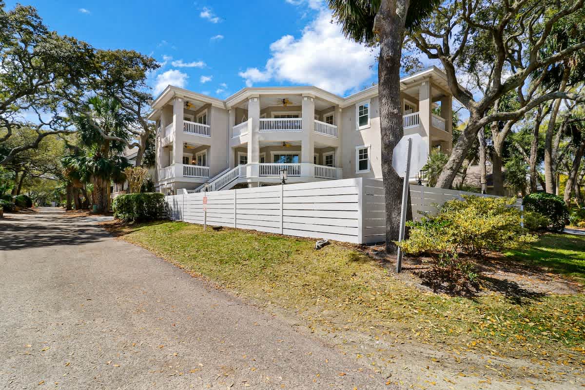 Elegant white property featuring spacious balconies and tropical landscaping in a peaceful residential setting.
