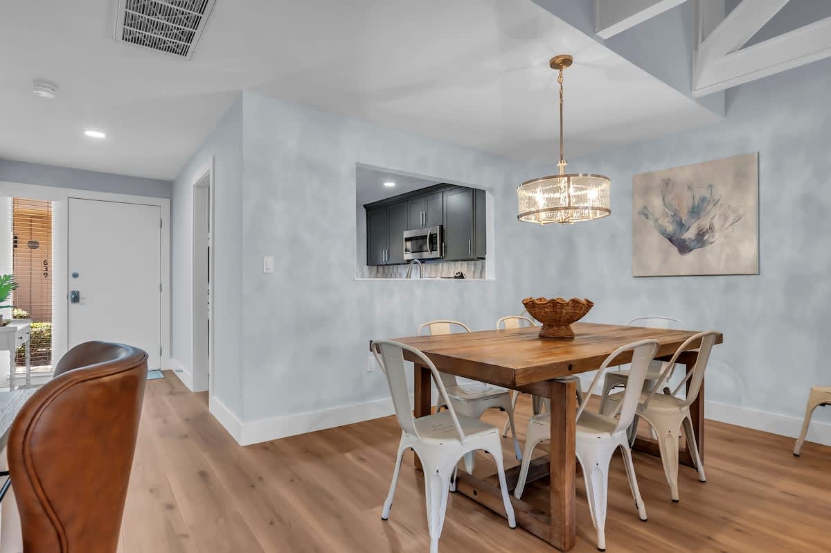 Gather around your rustic wooden dining table beneath crystal chandelier light, where memorable meals await in this modern coastal-chic space.