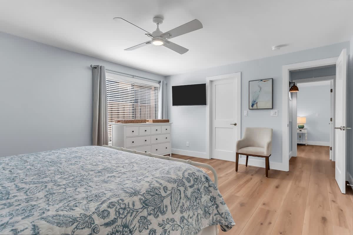 This spacious bedroom offers a tranquil escape with its crisp white palette, warm wood floors, and elegant coastal décor. It’s the perfect place to recharge after a sun-filled day on Hilton Head.