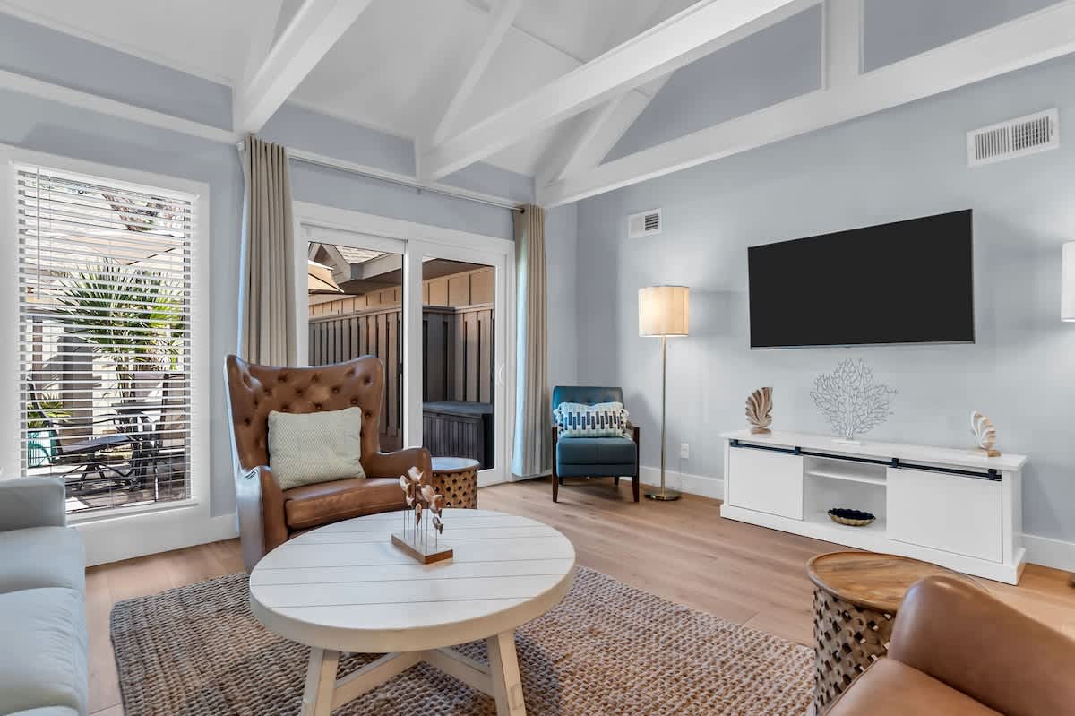 Unwind in your stylish living room with exposed beams, cozy leather seating, and patio access for perfect indoor-outdoor flow.