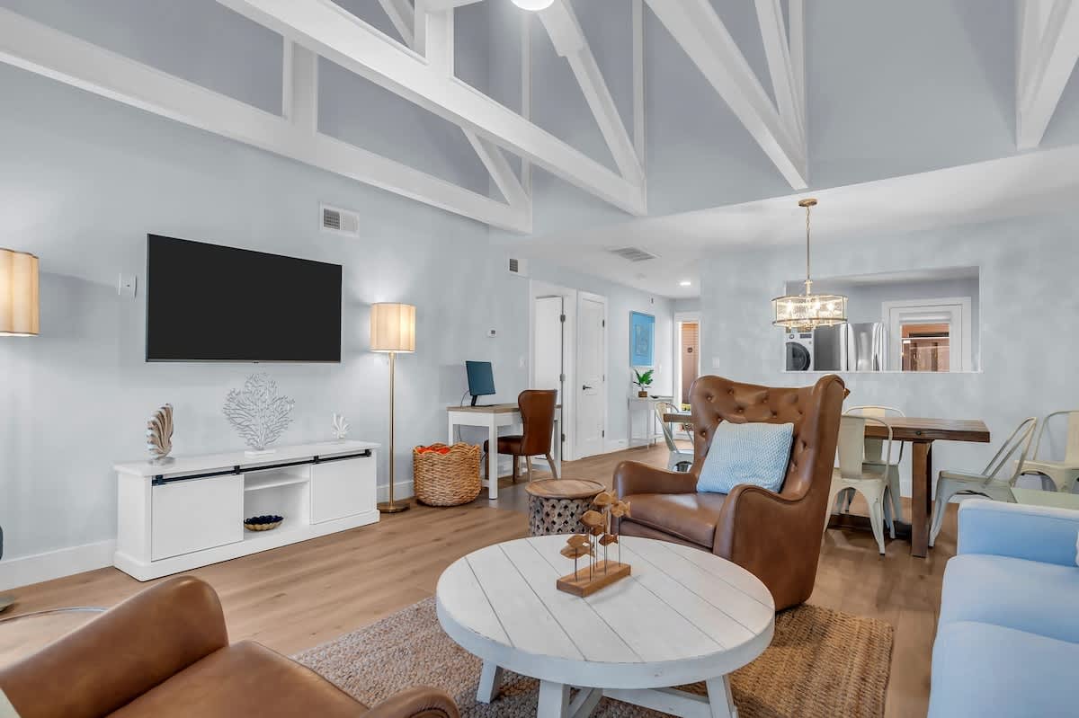 Unwind in this inviting coastal living area where vaulted ceilings and exposed beams create an airy, open feel. Supple leather chairs offer the perfect place to settle in after a sun-filled beach day