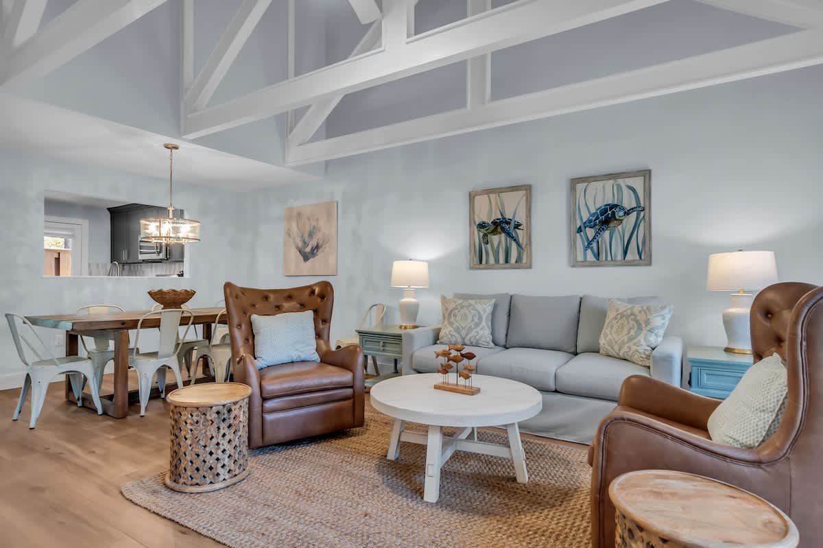 Relax in your coastal-chic living space with soaring beams, leather chairs, and soft blues creating the perfect beach retreat.