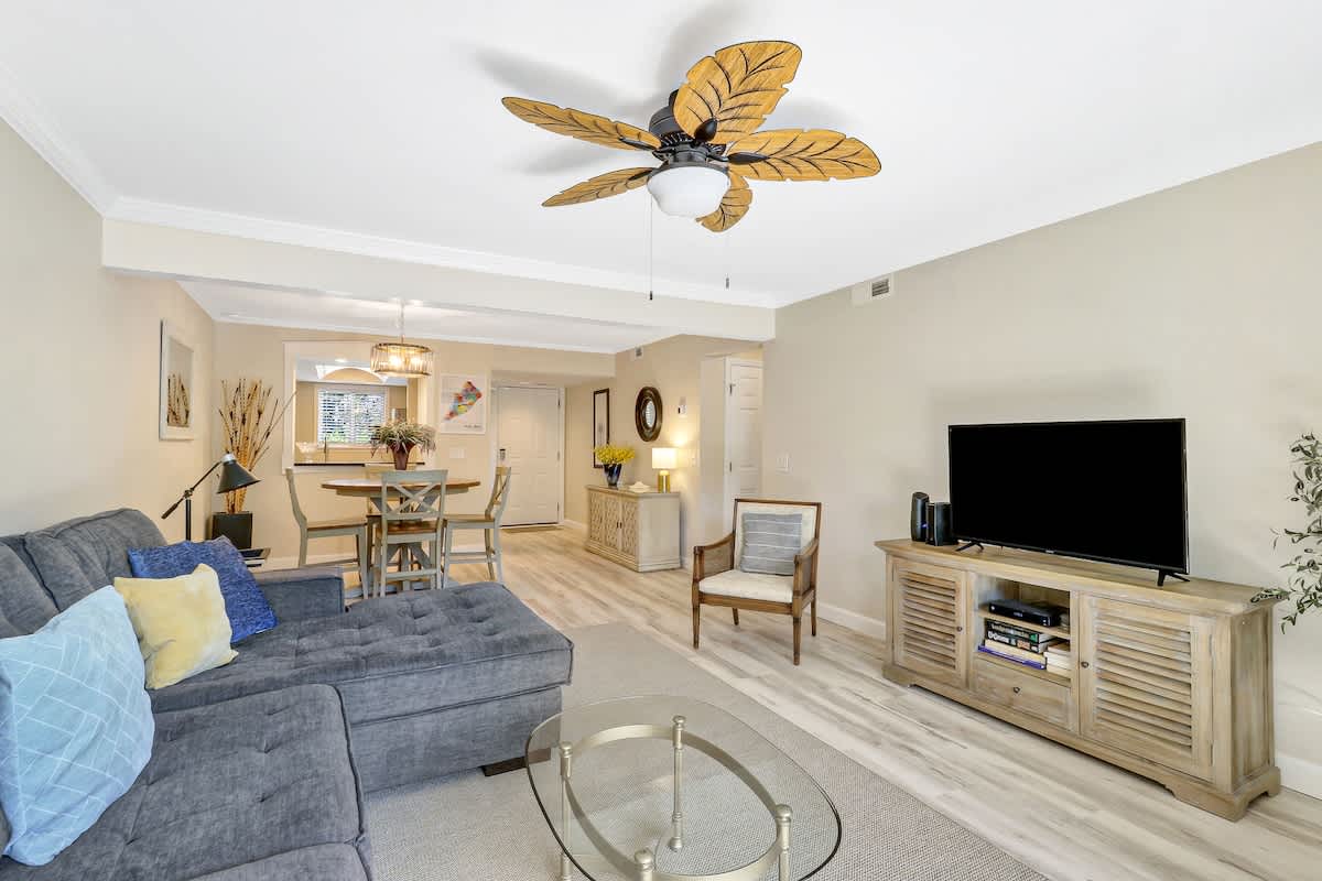Unwind in your spacious living area with coastal-inspired décor, plush seating, and tropical ceiling fan creating the perfect retreat.