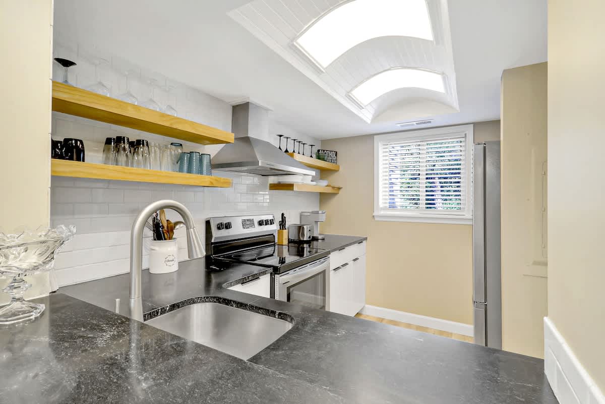 Cook with style in your modern kitchen featuring sleek countertops, open shelving, and abundant natural light from skylights above.