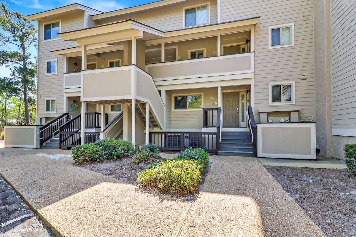 Multi-level vacation property with private balconies and landscaped grounds surrounded by mature trees.