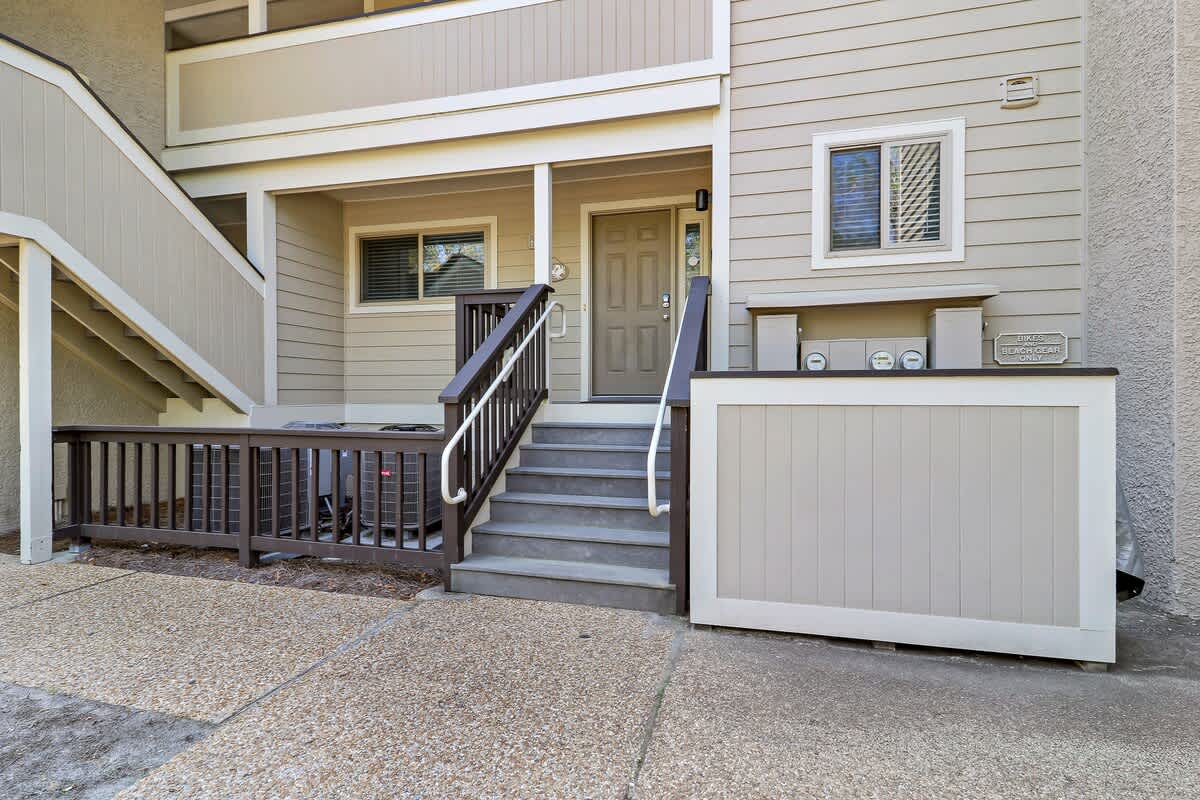 Multi-level property building with covered entrance stairs, outdoor railings, and ground-floor access features.
