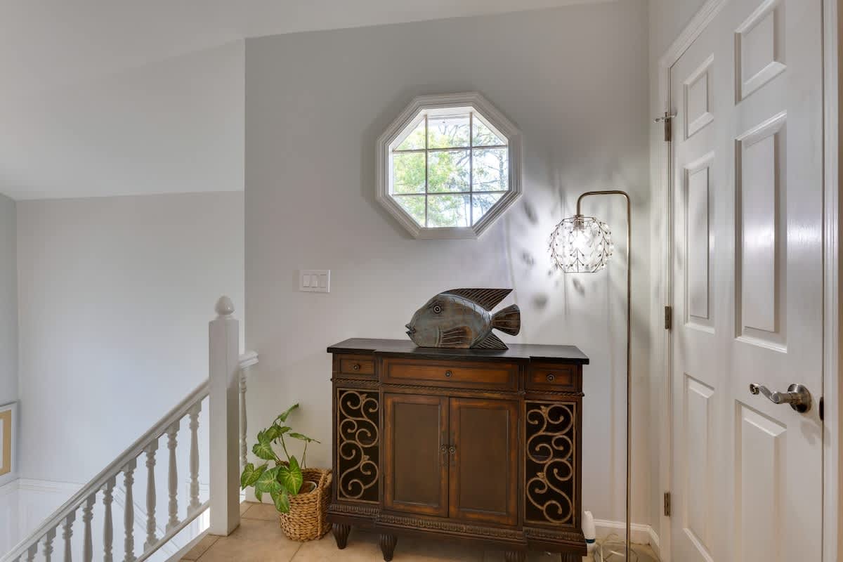 Sunlight streams through your octagonal window, illuminating this charming upstairs hallway with warm natural light and thoughtful coastal touches.