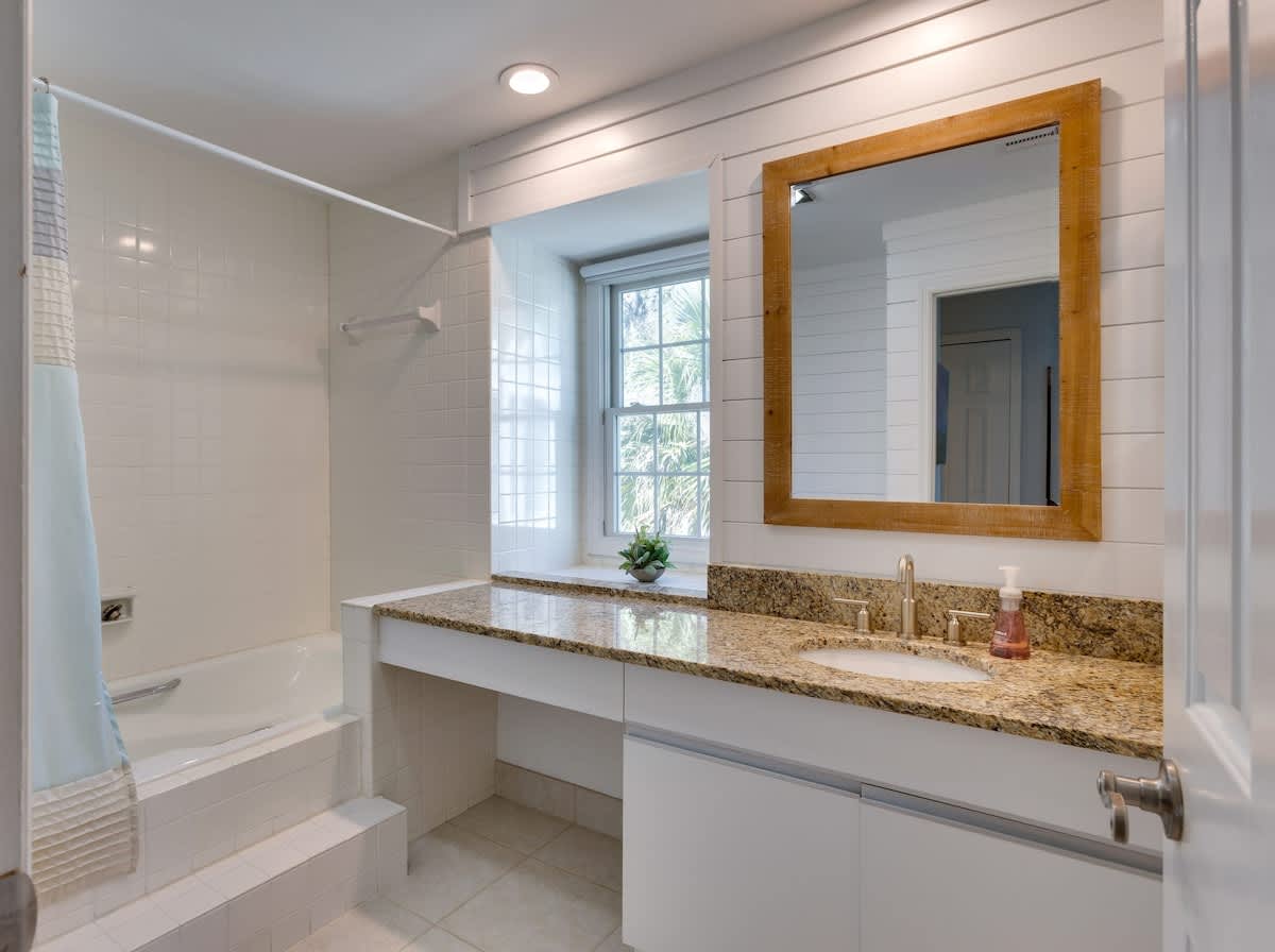 Refresh in your bright, modern bathroom featuring granite counters, elegant shiplap walls, and a relaxing tub-shower combo.