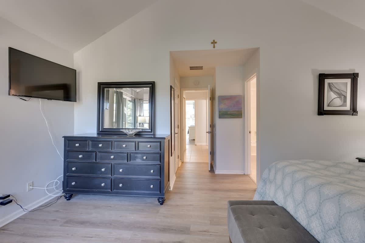 Your elegant bedroom features a spacious layout with stylish dark wood dresser, wall-mounted TV, and convenient storage for all your belongings.