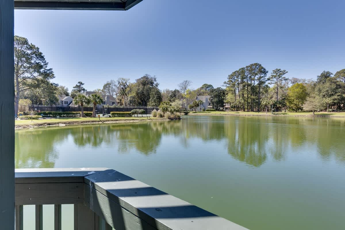 Lakefront view from covered porch showcases peaceful waters and wooded residential shoreline.
