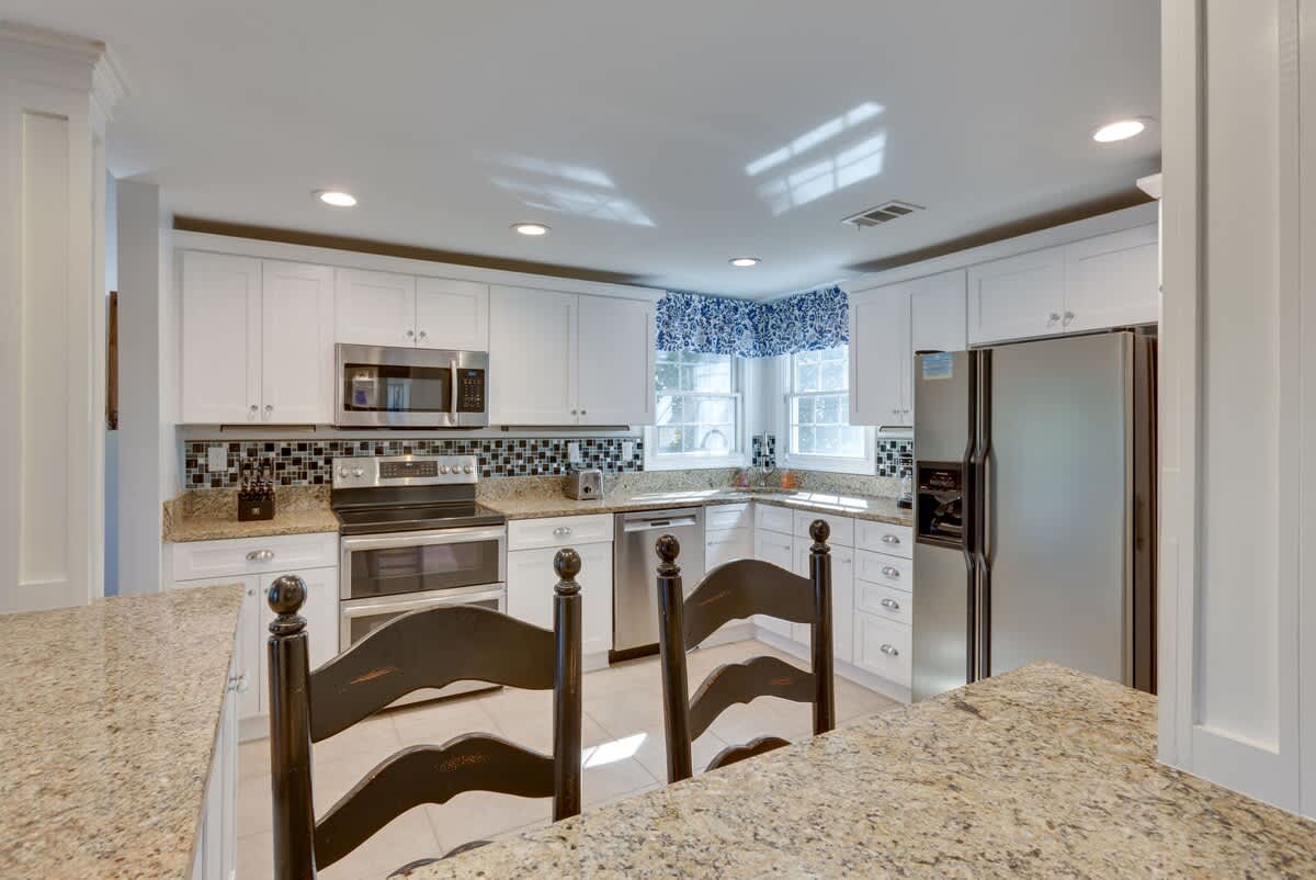 Your fully equipped kitchen features granite counters, modern appliances, and charming breakfast bar perfect for morning coffee.
