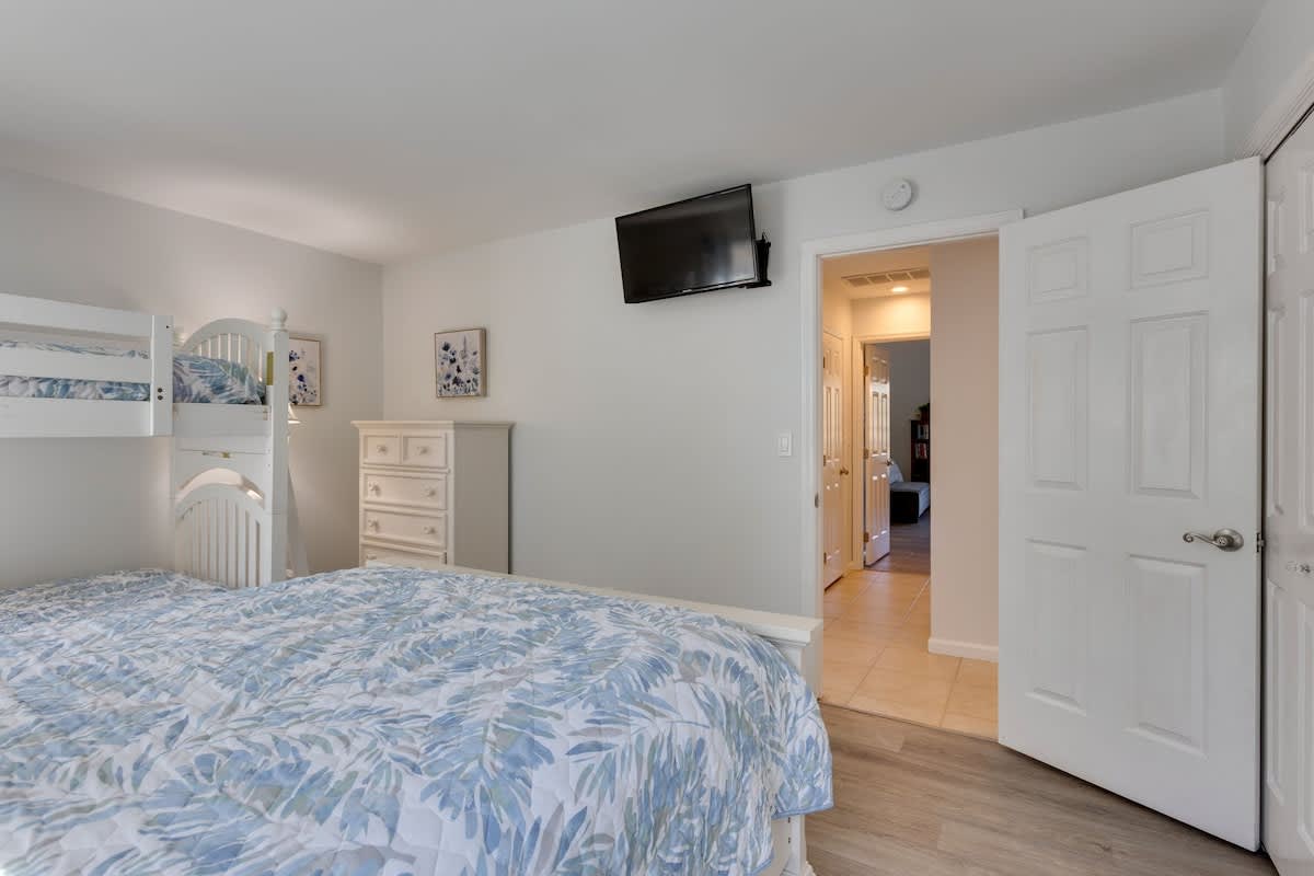 Your comfortable bedroom features a cozy bunk bed and queen bed with tropical-themed bedding, perfect for families.