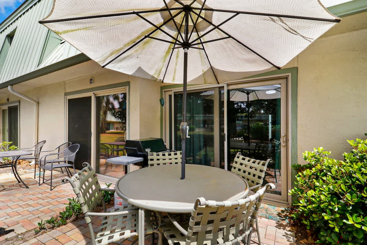 Your private patio offers shaded comfort with elegant outdoor dining and lounge seating surrounded by lush greenery.
