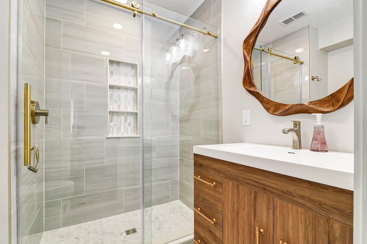 Indulge in your private spa-style retreat with gleaming marble tiles, brass fixtures, and a stunning live-edge wood mirror that adds warmth.