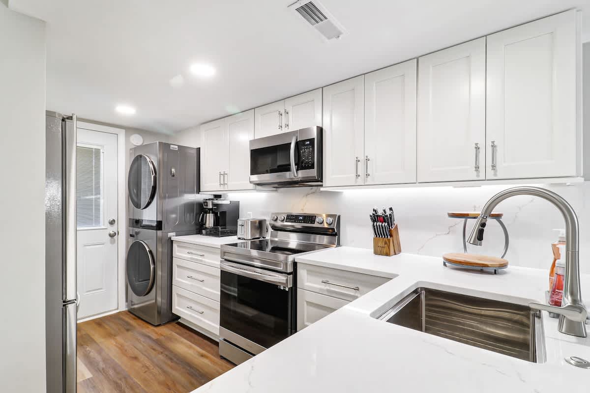 Fully equipped kitchen features modern appliances, white cabinetry, and quartz countertops perfect for preparing your favorite meals.