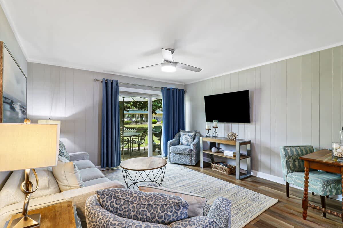 Relax in this beautifully designed living room with comfortable seating, modern TV, and peaceful garden views through sliding doors.