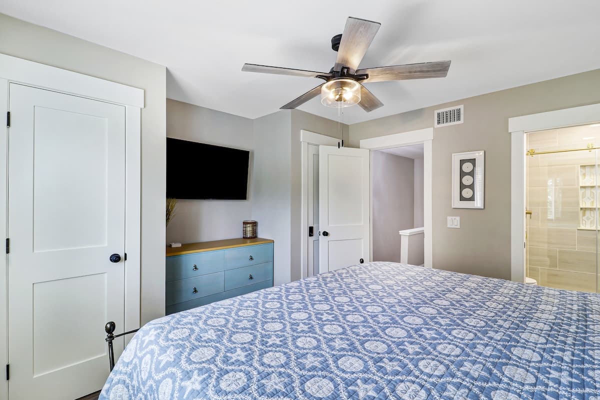 Drift off to sleep in your serene bedroom, where ceiling fan breezes and soft blue patterns create the perfect peaceful retreat.