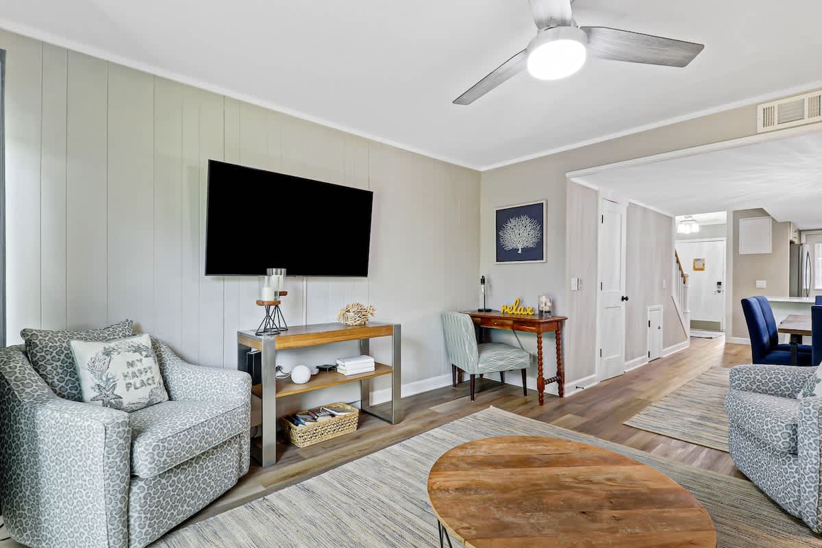 Unwind in your spacious living room with comfortable patterned seating, a large TV for entertainment, and coastal charm throughout.