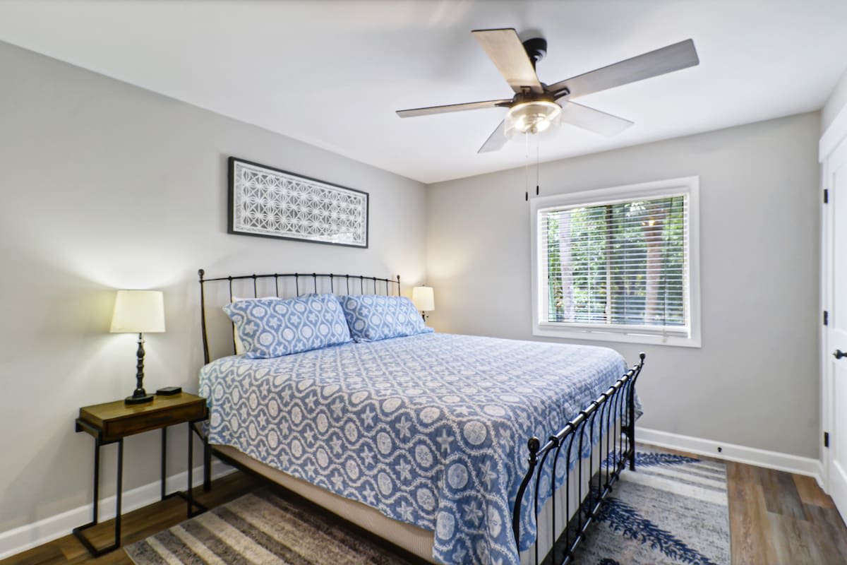 Drift off peacefully in your serene bedroom with soft blue linens, natural light, and a gentle ceiling fan overhead.
