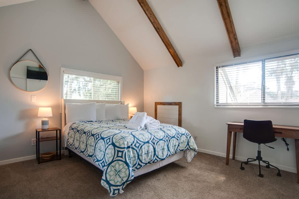 Relax in your bright bedroom featuring exposed beams, comfortable queen bed, and dedicated workspace for business or leisure.