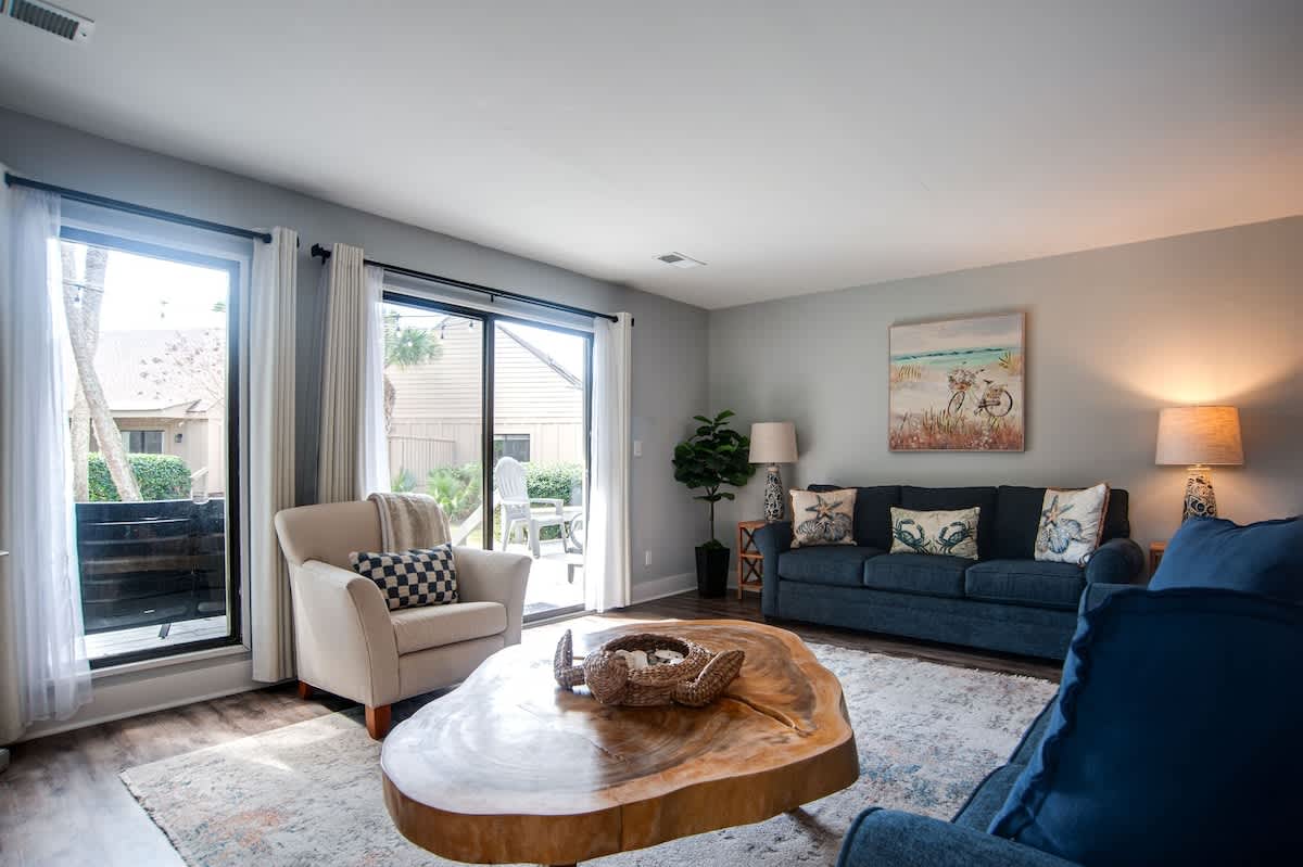 Sink into plush navy sofas while natural light floods your cozy retreat through sliding glass doors to your private patio.