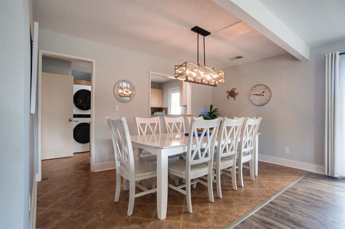 Gather your group around this spacious dining table for memorable meals together, bathed in warm light from the stunning geometric chandelier.