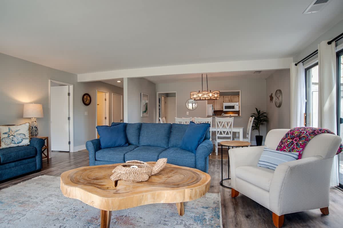 Sink into your plush blue sofa and unwind in this bright, open living space where coastal charm meets modern comfort.